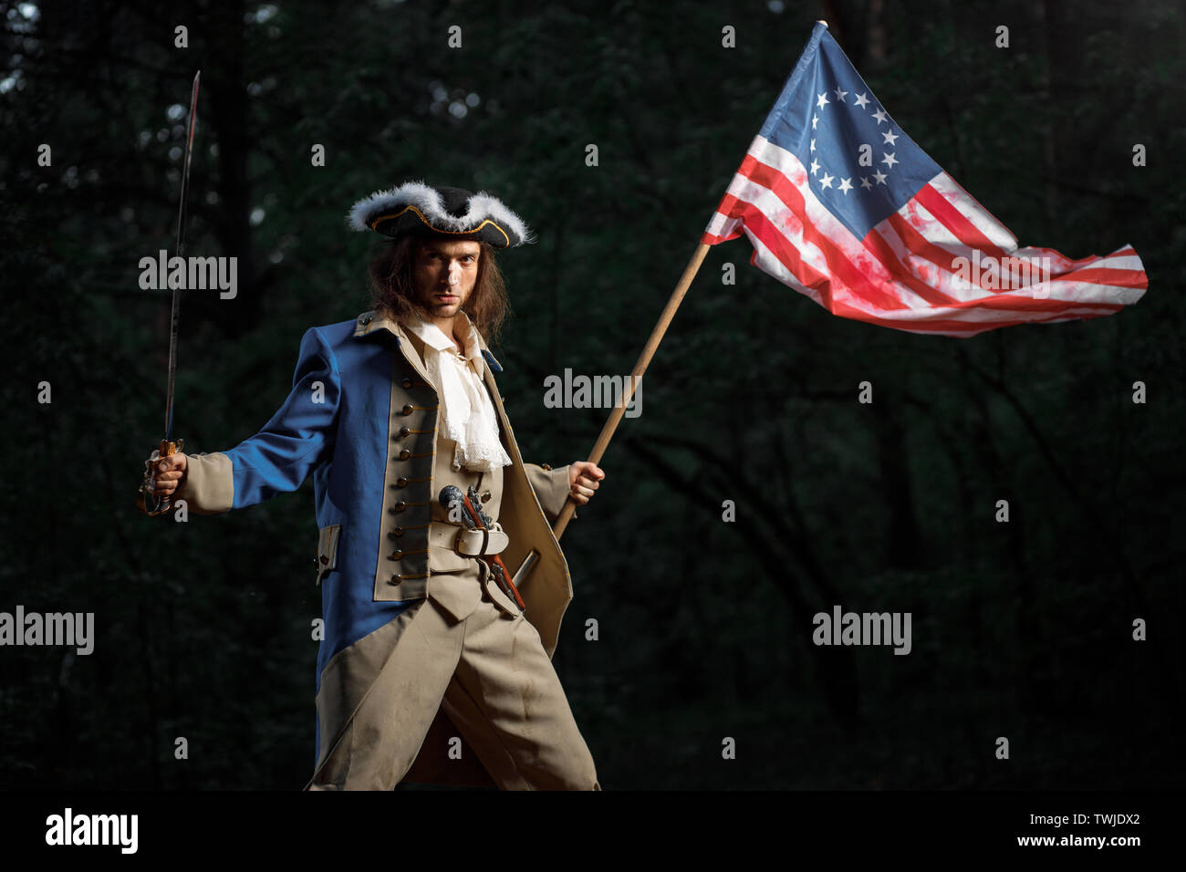 Soldier patriot rebel during war of independence of  United States with flag preparing to attack with sword Stock Photo