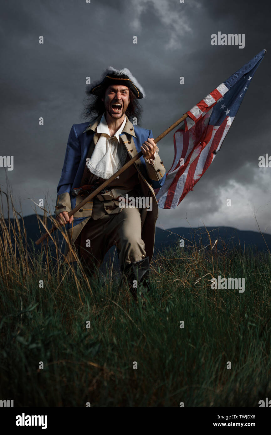 American revolution war soldier with flag of colonies over dramatic landscape. 4 july independence day of USA concept photo composition: soldier and f Stock Photo