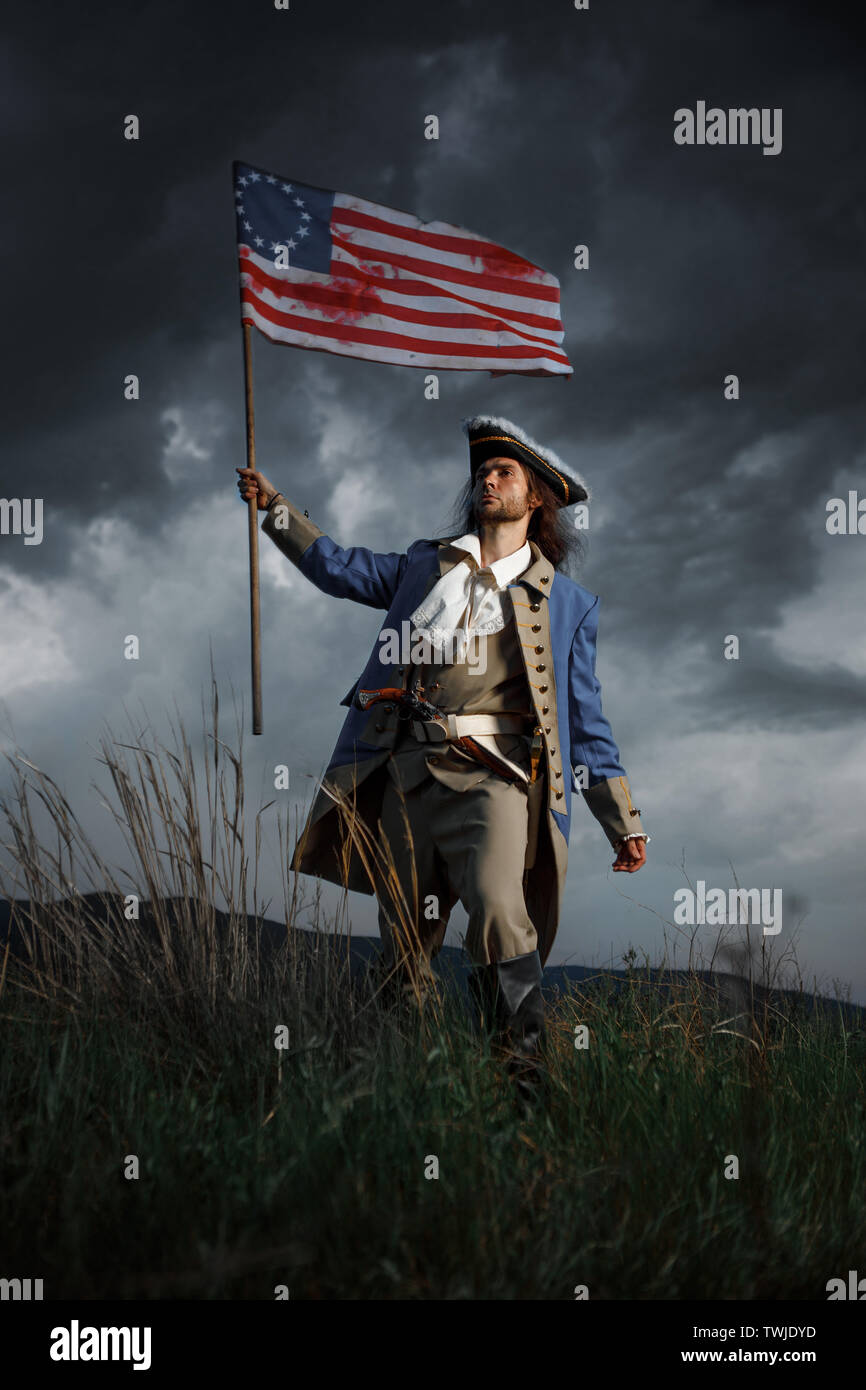 American revolution war soldier with flag of colonies over dramatic landscape. 4 july independence day of USA concept photo composition: soldier and f Stock Photo