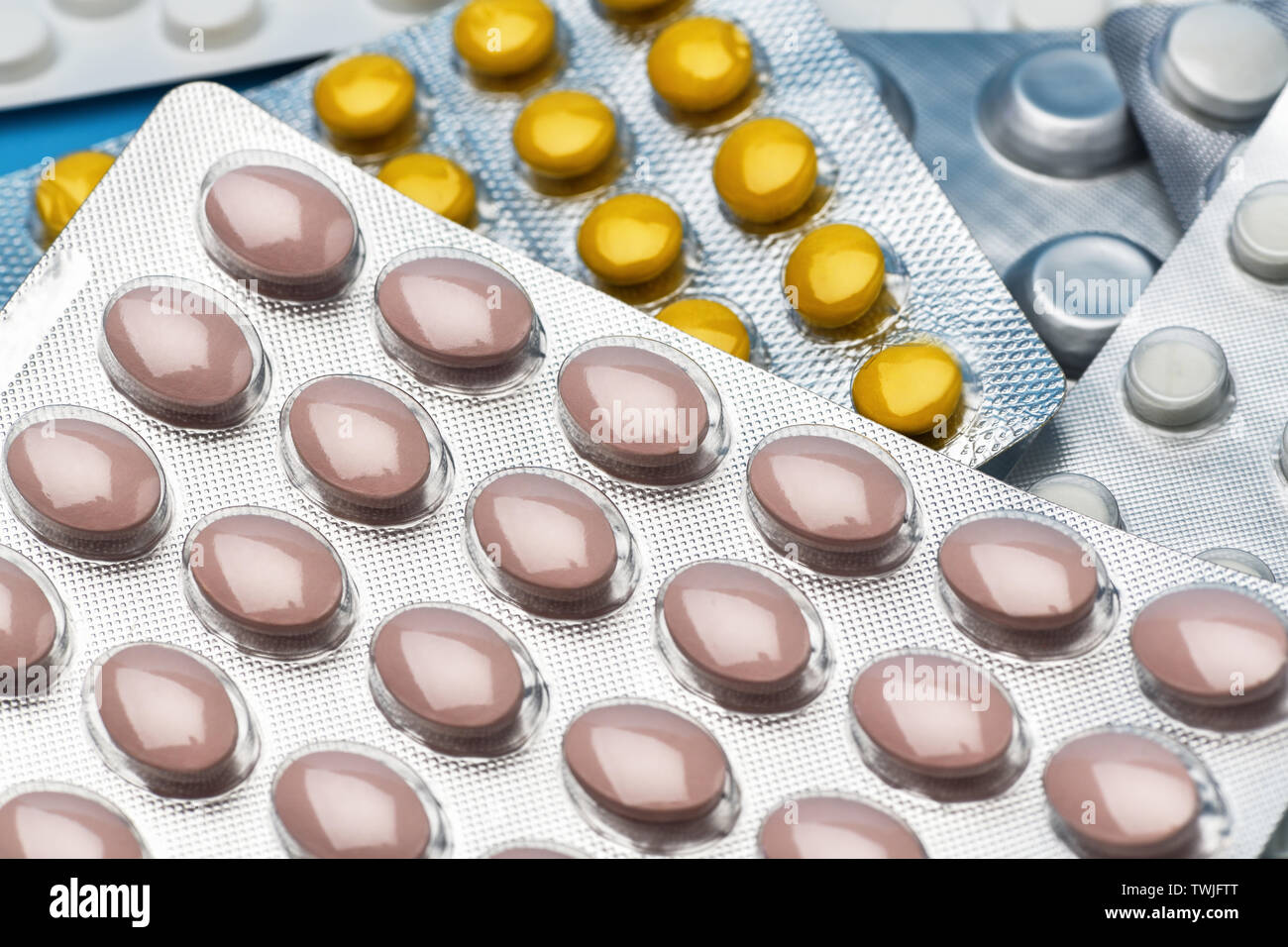 Pile of colorful medicine pills and capsules . A lot of packages of multicolored pills lying on blue background Stock Photo