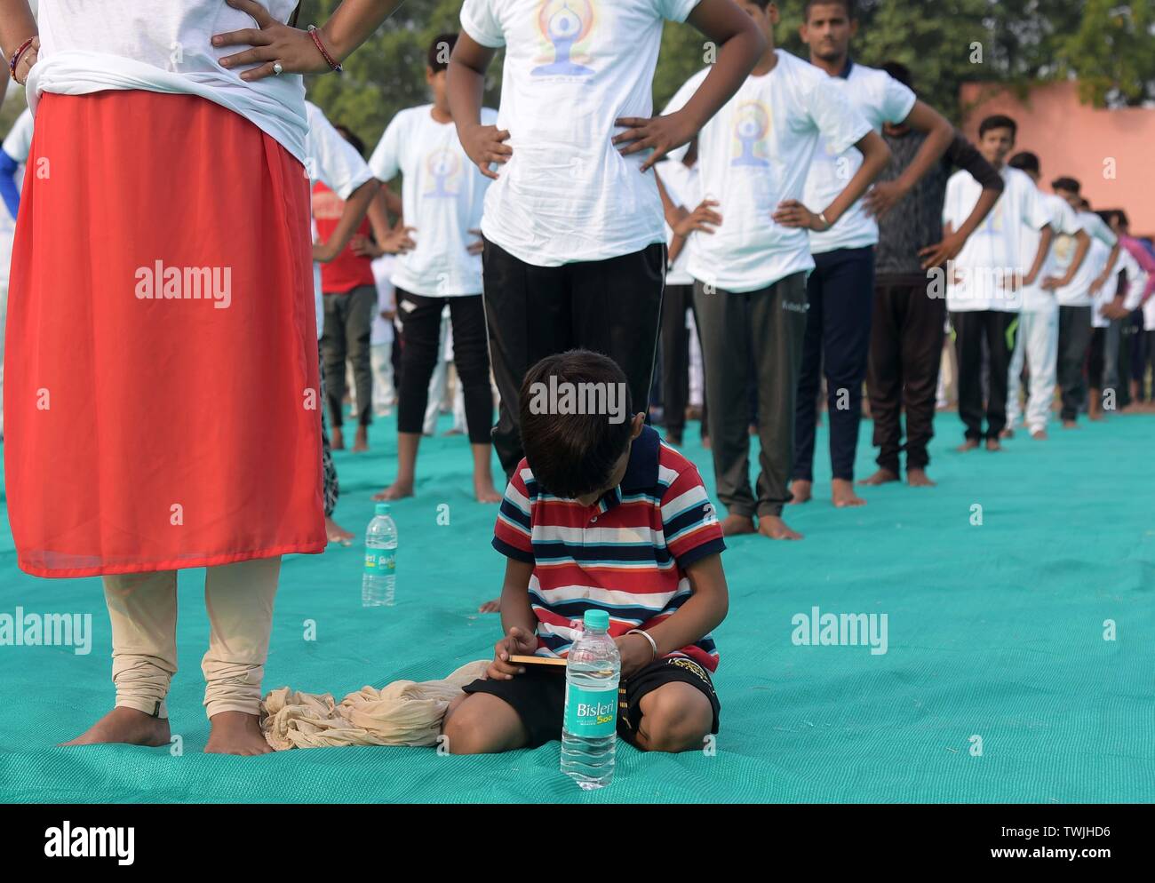 Allahabad, Uttar Pradesh, India. 21st June, 2019. Allahabad: A child busy in smart phone as her mother performing Yoga on the occasion of 5th International Yoga Day celebration at Madan Mohan malviya Stadium in Allahabad on May 21, 2019. Credit: Prabhat Kumar Verma/ZUMA Wire/Alamy Live News Stock Photo