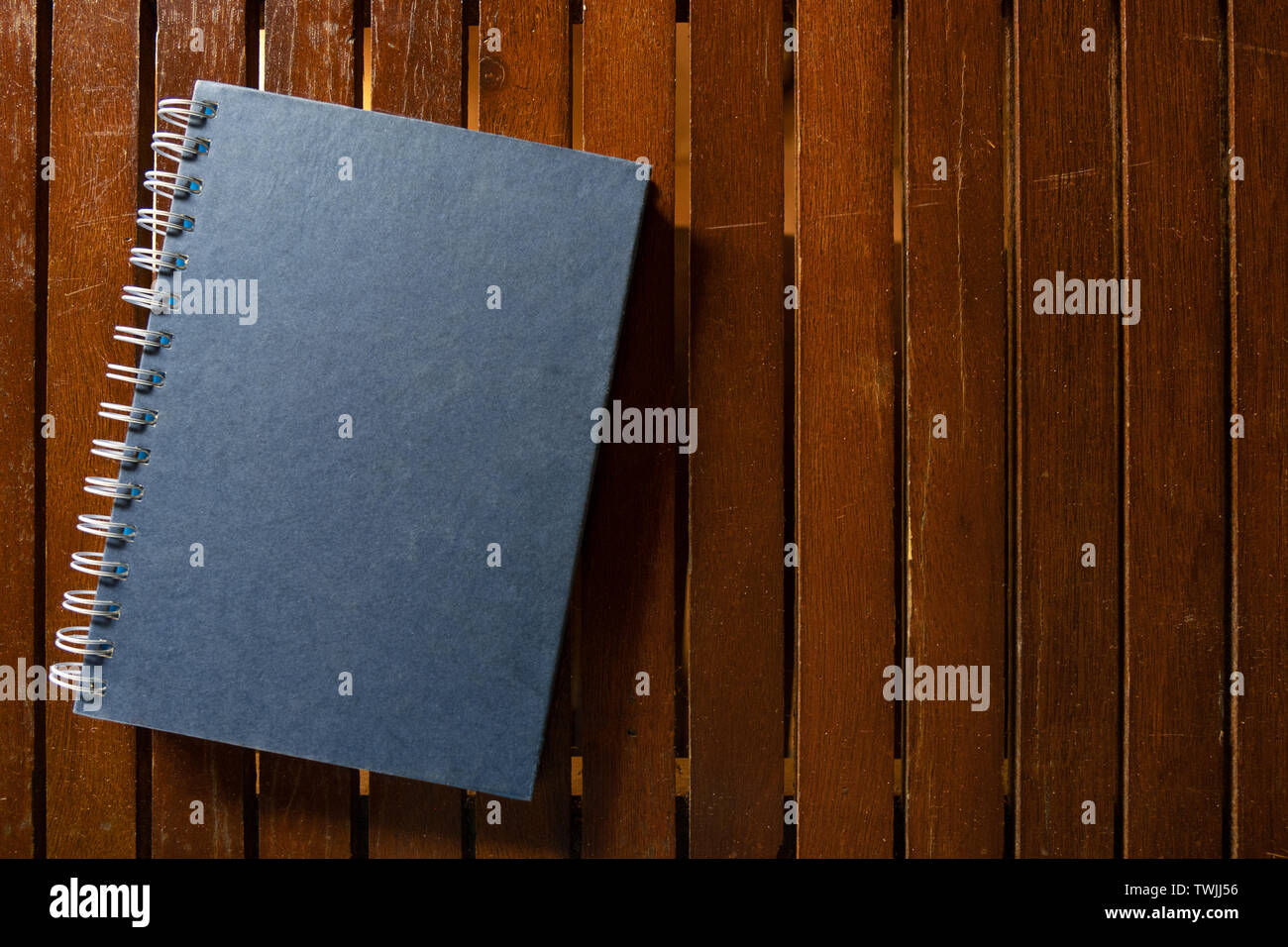 Dark blue closed hardcover book on wooden table. Top view with copy space Stock Photo