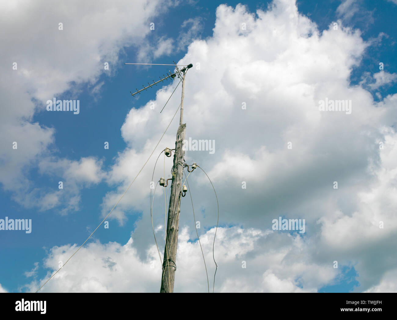 Abandoned wooden electrical post with dandling wires against the blue sky, concept of a blackout Stock Photo