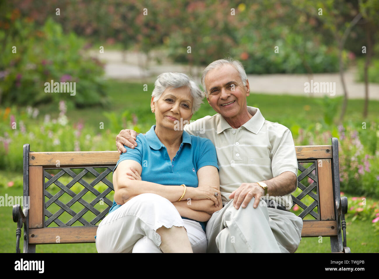 Old couple sitting on a park bench and smiling Stock Photo - Alamy