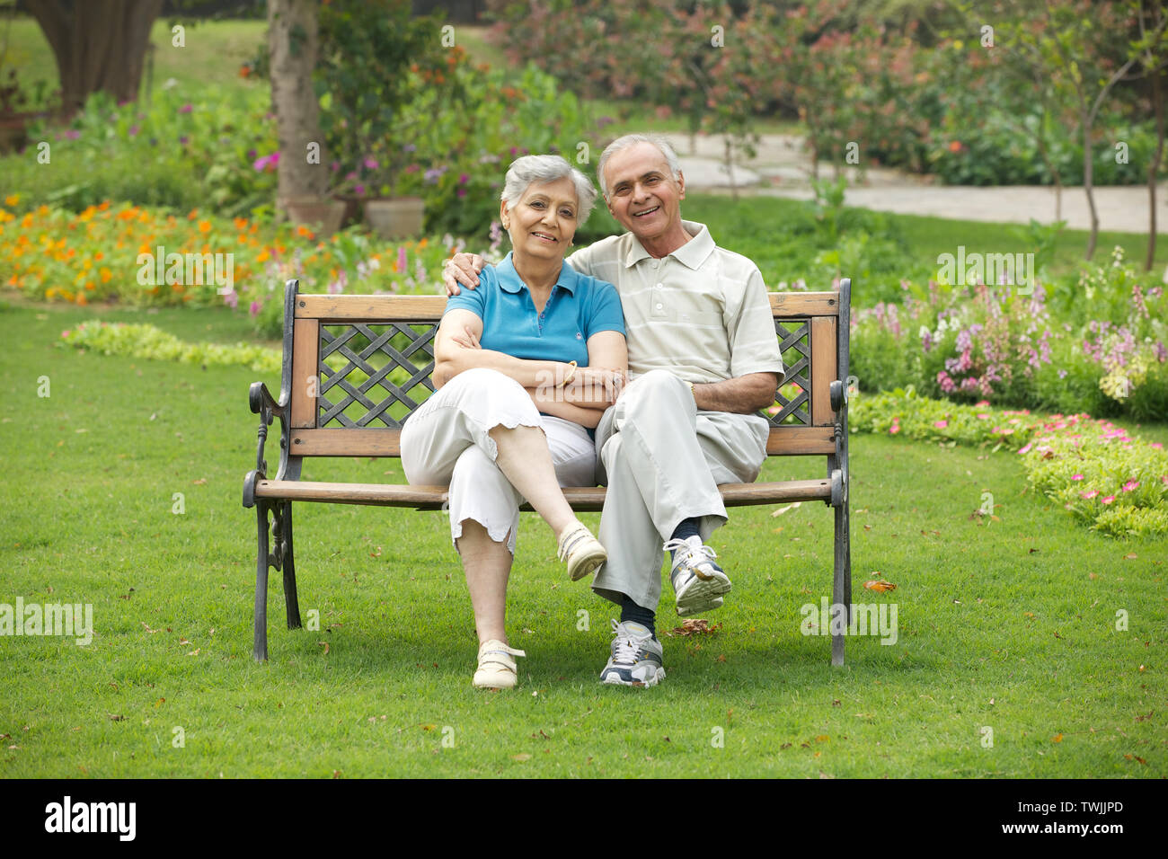 Old couple sitting on a park bench and smiling Stock Photo - Alamy
