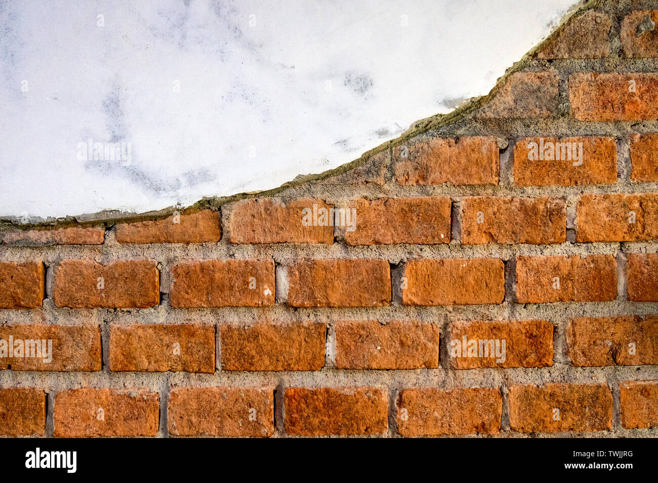 Weathered cracked orange bricks with plaster background Stock Photo
