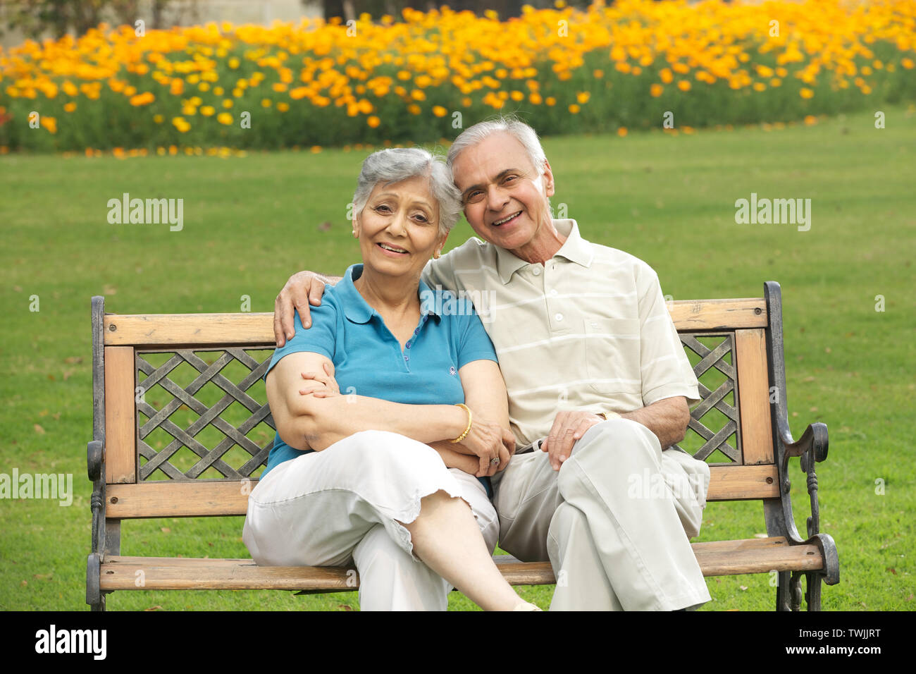 Old couple sitting on a park bench and smiling Stock Photo - Alamy