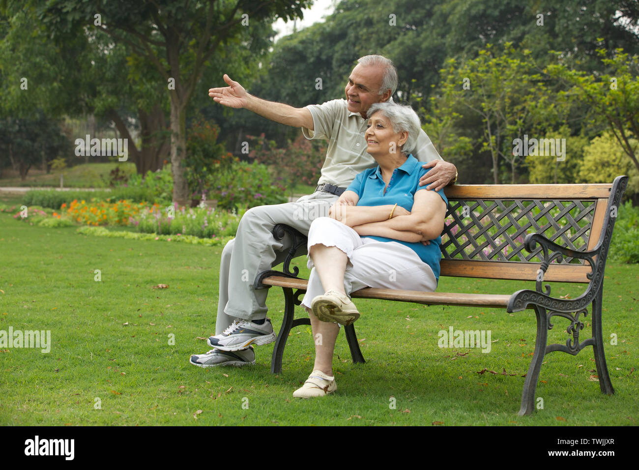 Old couple sitting on a park bench and smiling Stock Photo - Alamy