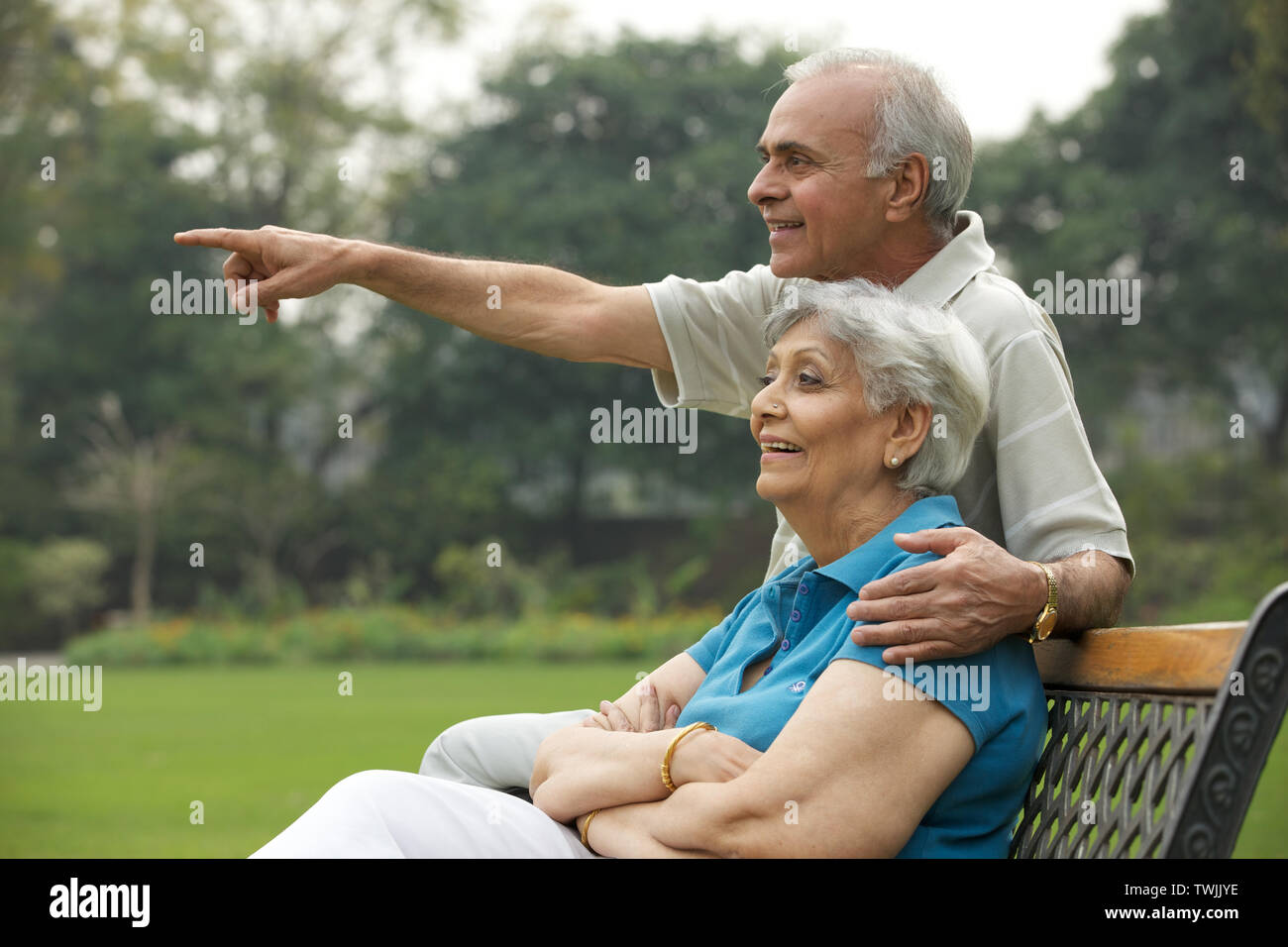 Old couple sitting on a park bench and smiling Stock Photo - Alamy
