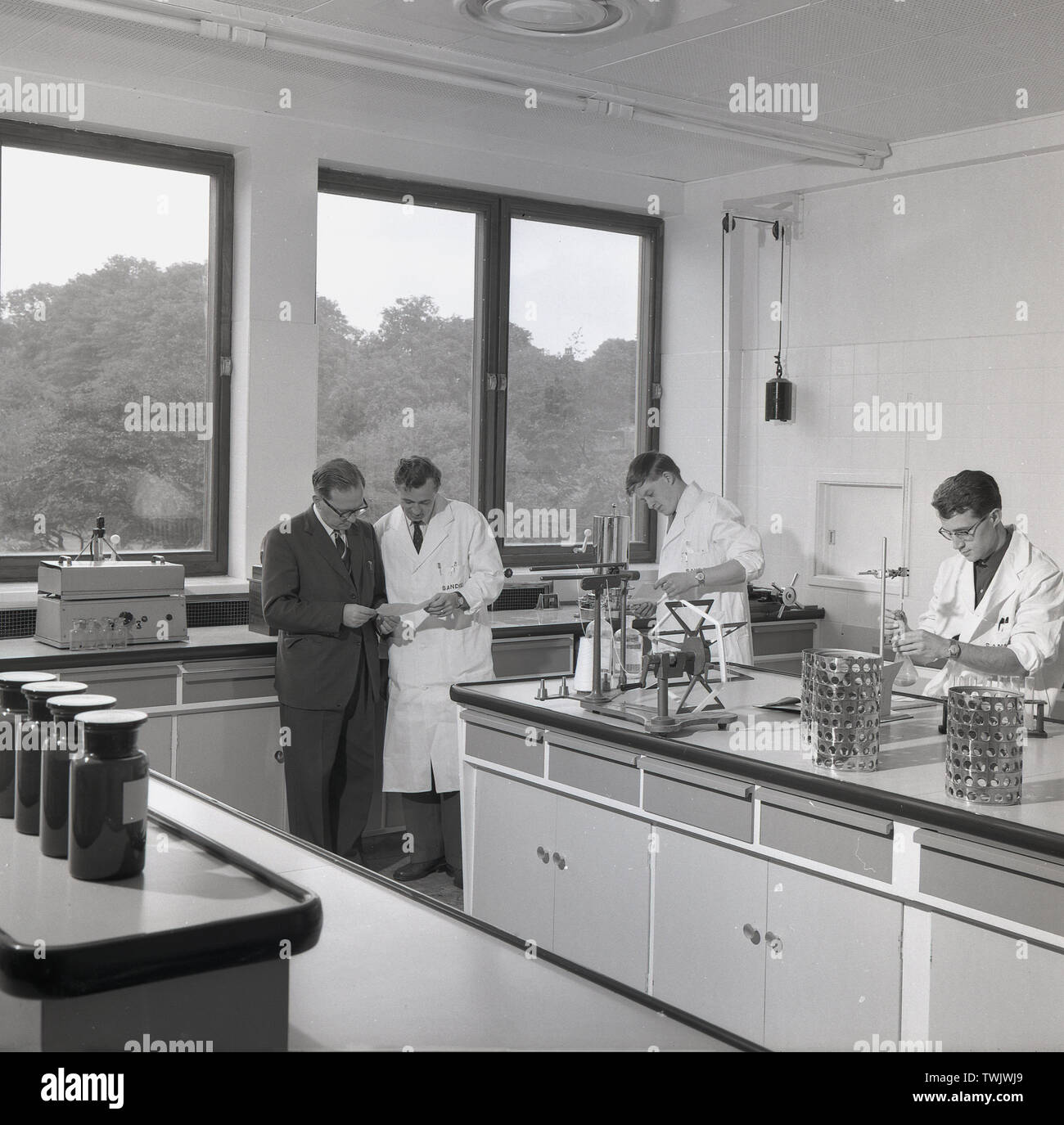 1950s, historical picture showing two mangers and two young male research scientists at work in a brightly lit, modern, purpose built laboratory at the Sandoz chemical company at Horsforth, Leeds, England, UK. The company made dyes for use in the textile and paper industries. Stock Photo