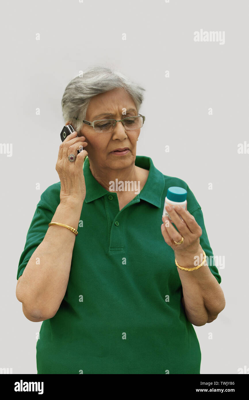 Old woman talking on a mobile phone and holding pill bottle Stock Photo ...