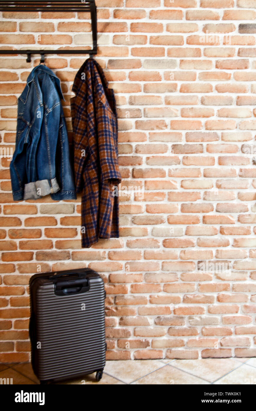 https://c8.alamy.com/comp/TWK0K1/modern-hallway-loft-interior-with-denim-coat-and-jacket-on-hanger-and-suitcase-against-brick-wall-with-copy-space-TWK0K1.jpg