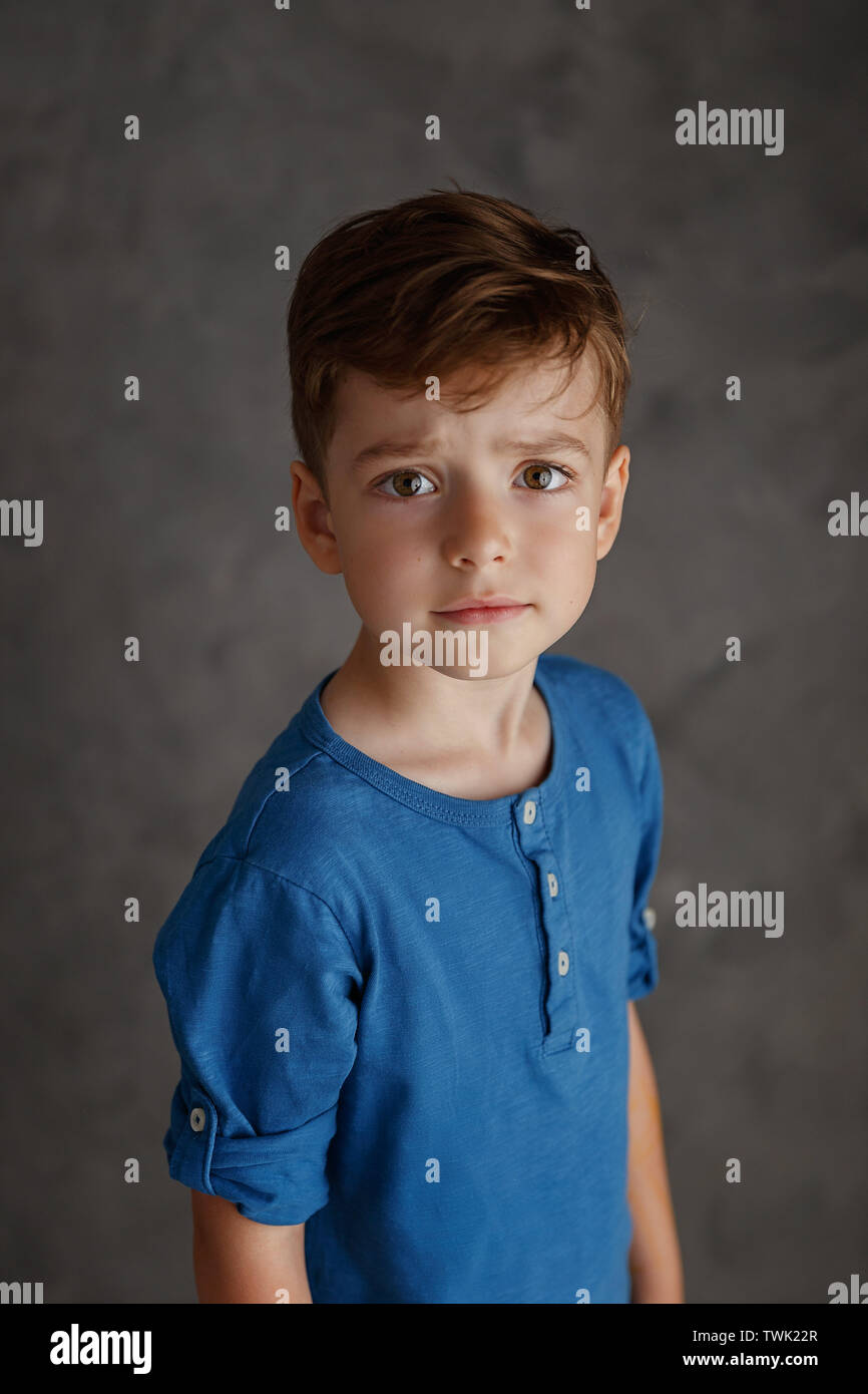 5 year old boy blue shirt and yellow pants studio portrait on gray