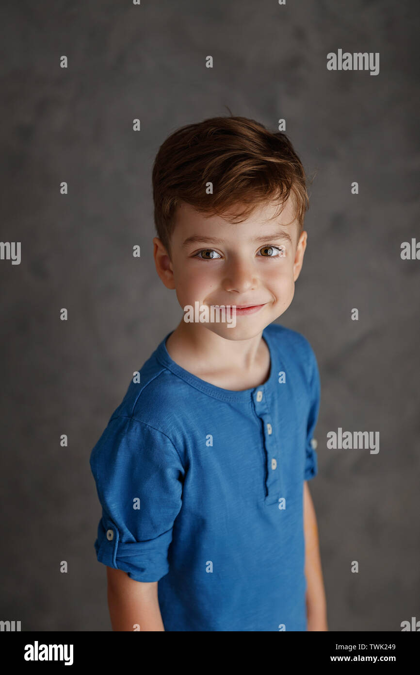 5 year old boy blue shirt and yellow pants studio portrait on gray background. Stock Photo