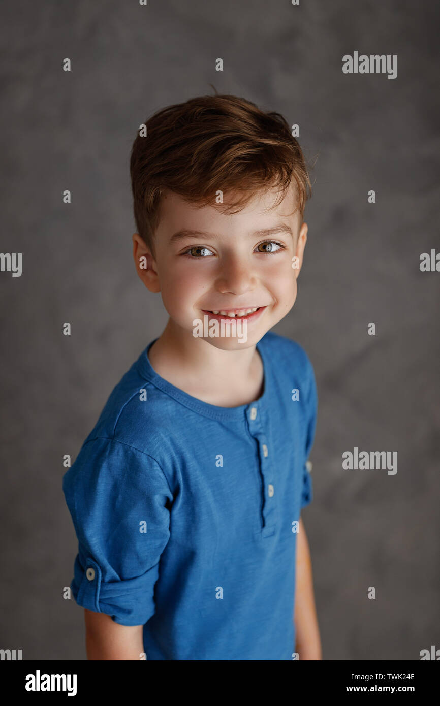 5 year old boy blue shirt and yellow pants studio portrait on gray