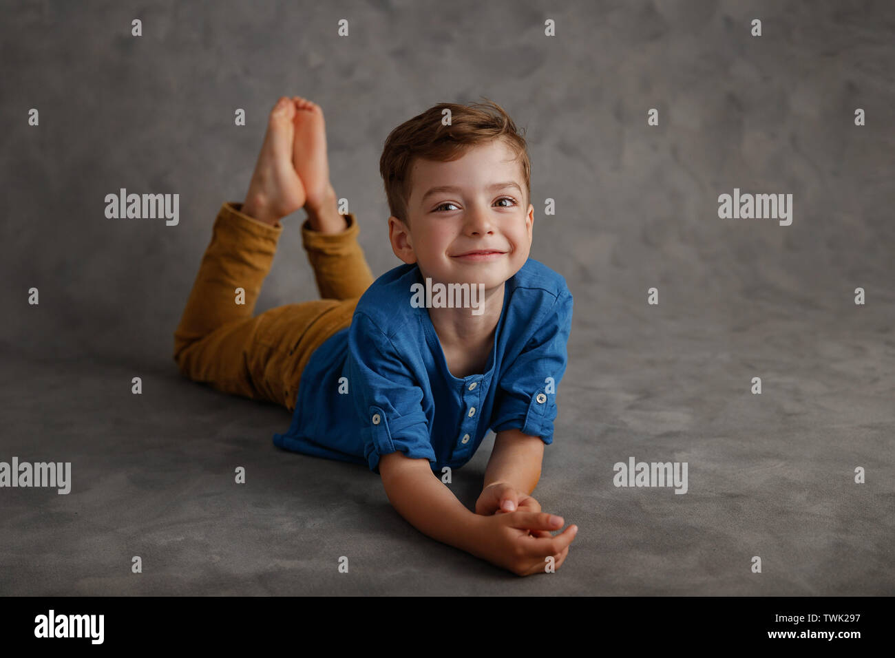 5 year old boy blue shirt and yellow pants studio portrait on gray background. Stock Photo
