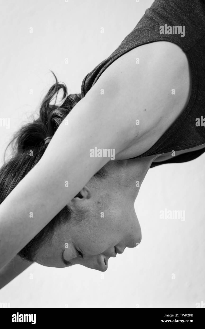 Close-up of a young woman performing the Adho Mukha Svanasana or downward-facing dog, one of yoga's most widely recognized yoga poses. Stock Photo