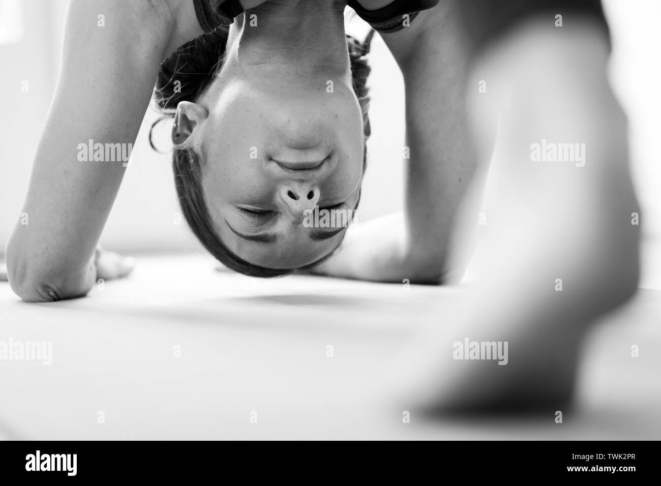 Close-up of a young woman performing the Adho Mukha Svanasana or downward-facing dog, one of yoga's most widely recognized yoga poses. Stock Photo