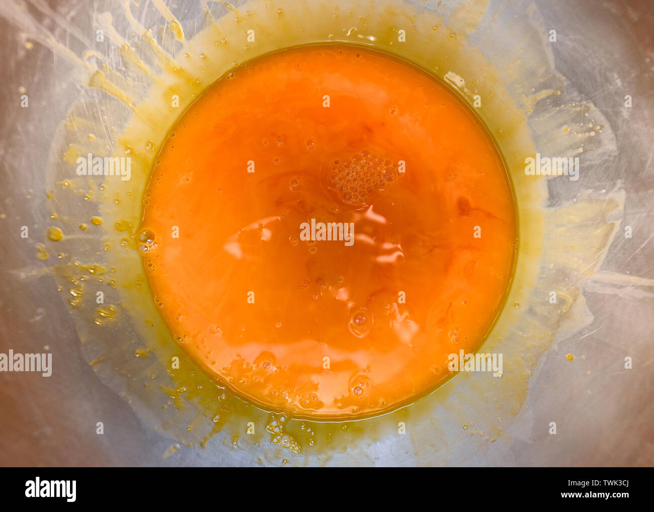 Orange color fluid of yolk stir in stainless bowl Stock Photo