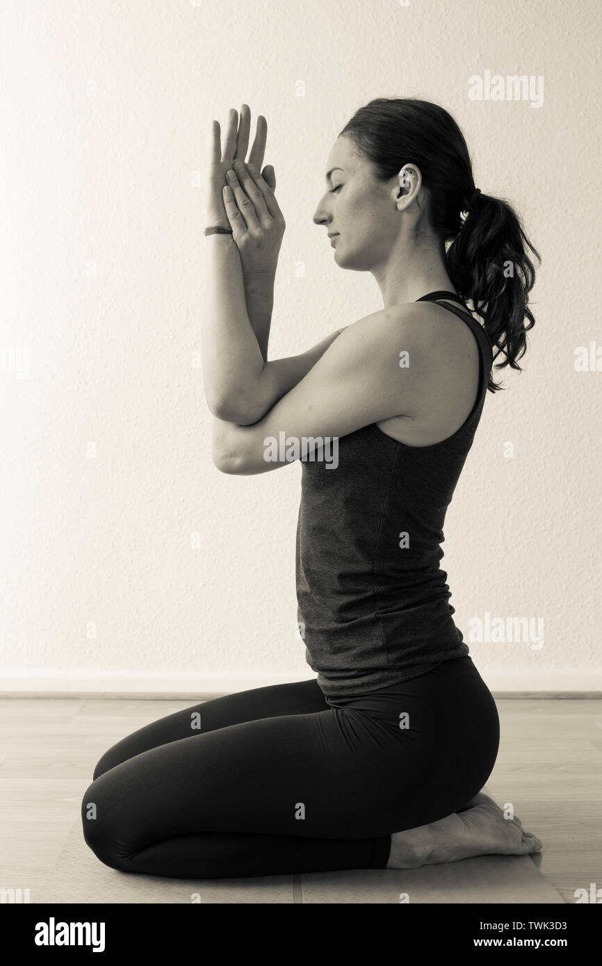 Young focused female in white sportswear performing Seated Eagle exercise  or Garudasana pose while practicing yoga in light room Stock Photo - Alamy