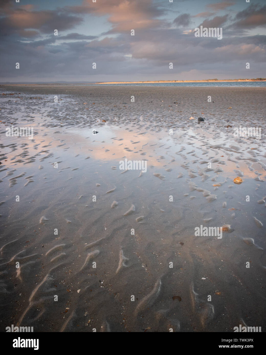 sunset clouds reflecting on wet sands at the beach Stock Photo