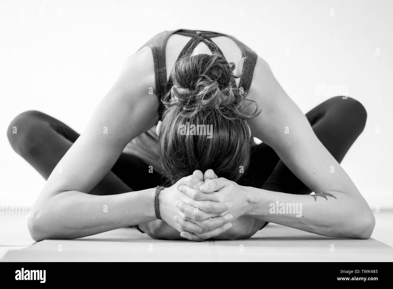 A brunette European woman practices the Star Pose or Tarasana yoga posture. Black and white, horizontal close-up view. Stock Photo