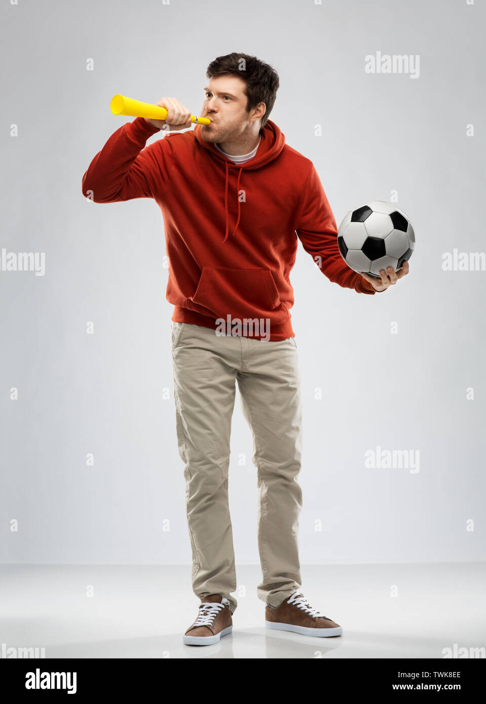football fan with soccer ball blowing horn Stock Photo Alamy