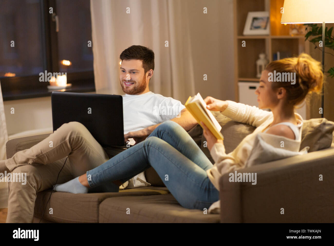 couple with laptop computer and book at home Stock Photo