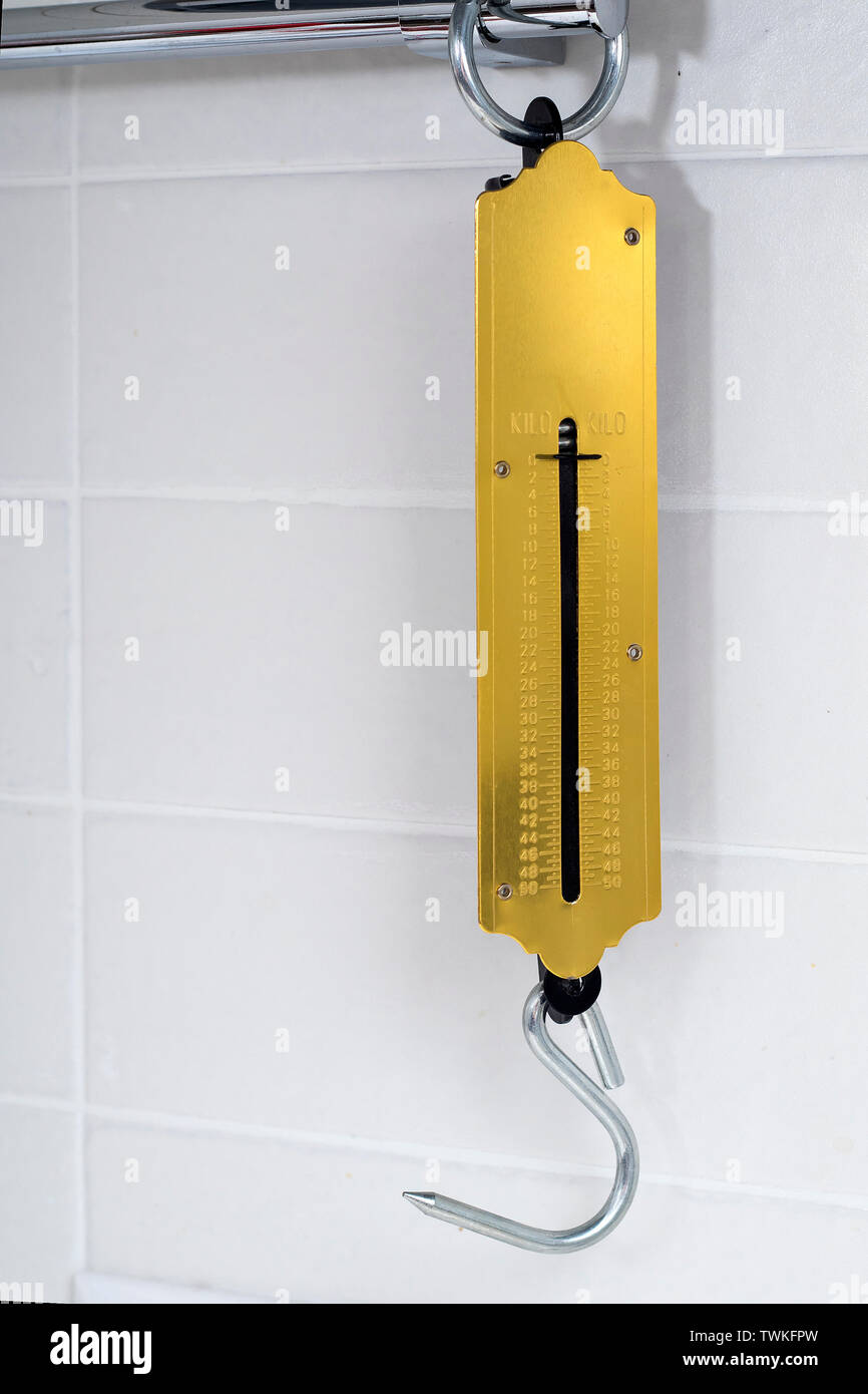 Scales for weighing products in the kitchen hang on a white hook