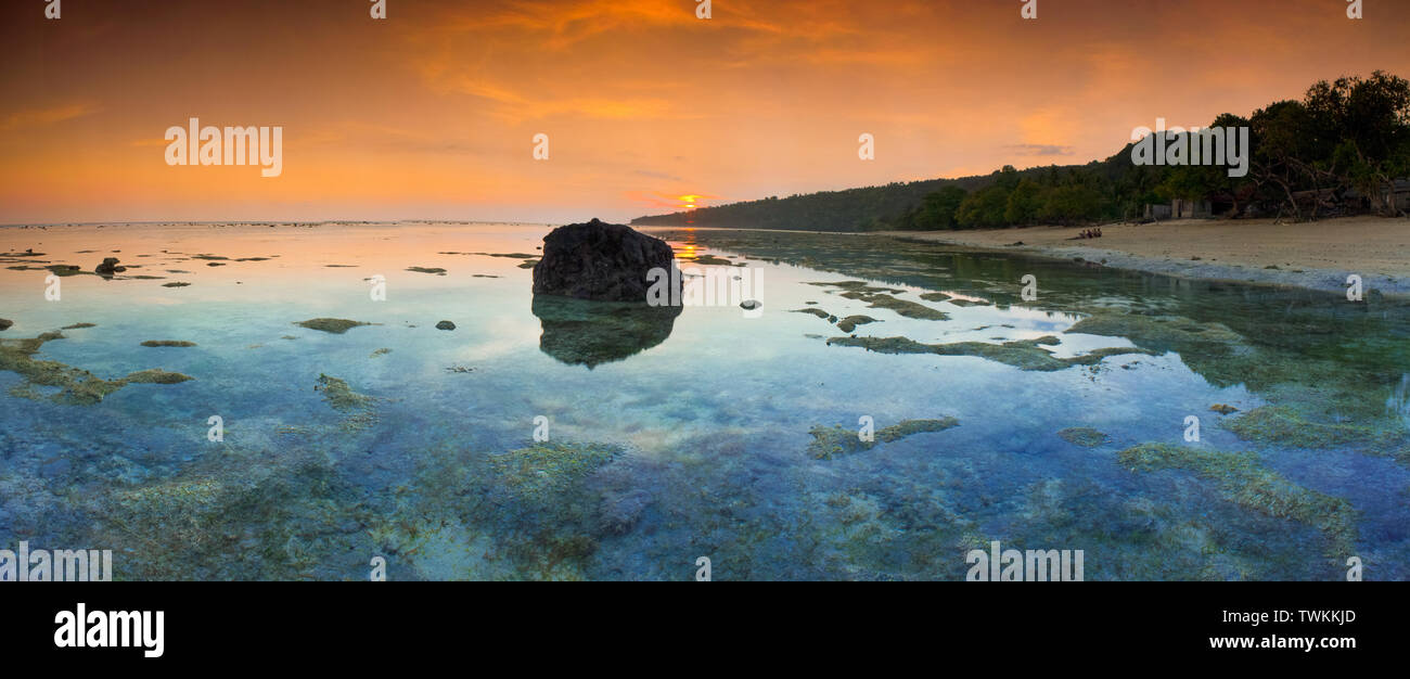 A panoramic view of the Flores sea with clear sea water and a dramatic sunset. Coral reefs are clearly visible because of the clarity of the water Stock Photo