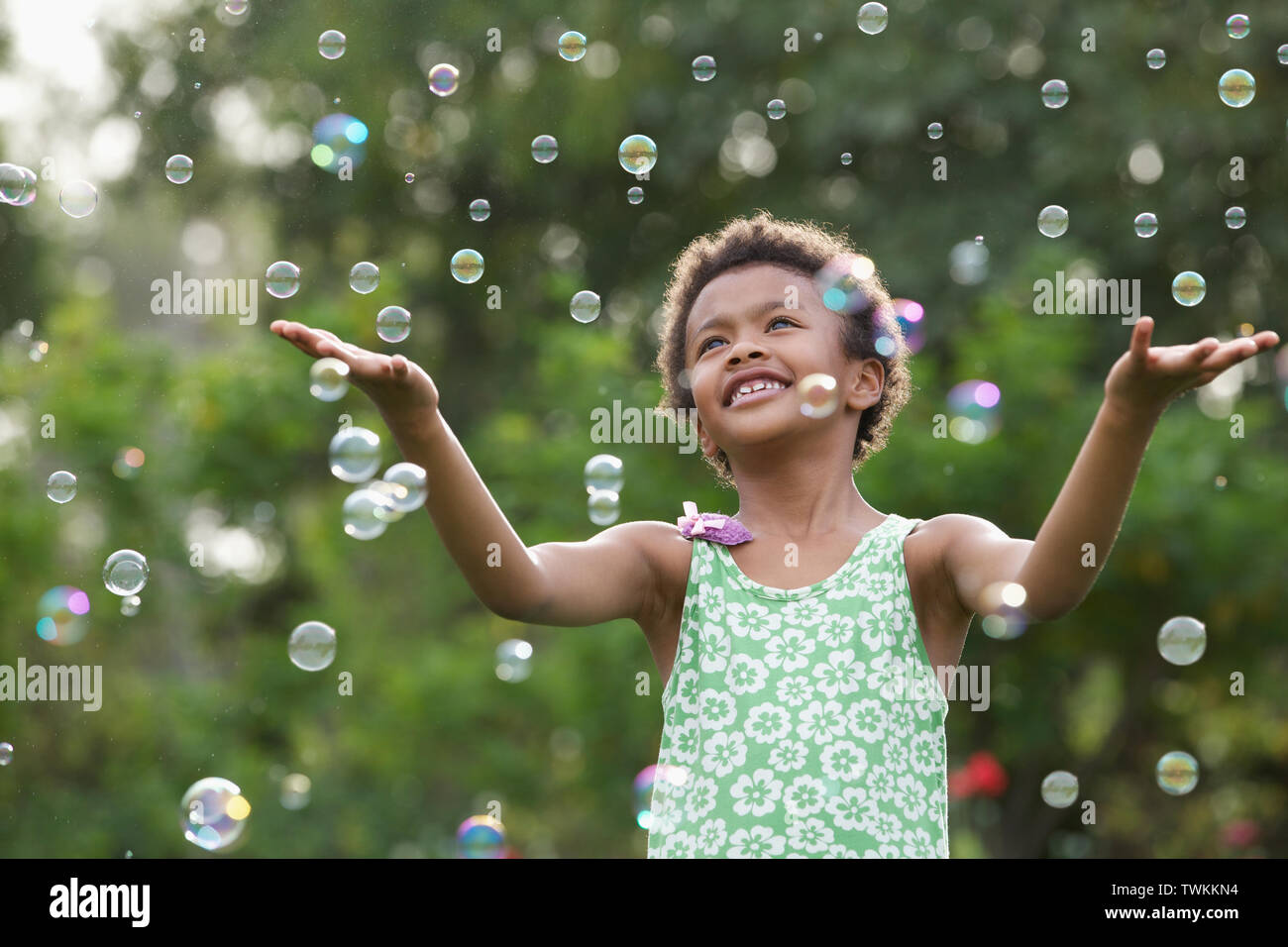 Girl trying to hold floating bubbles Stock Photo