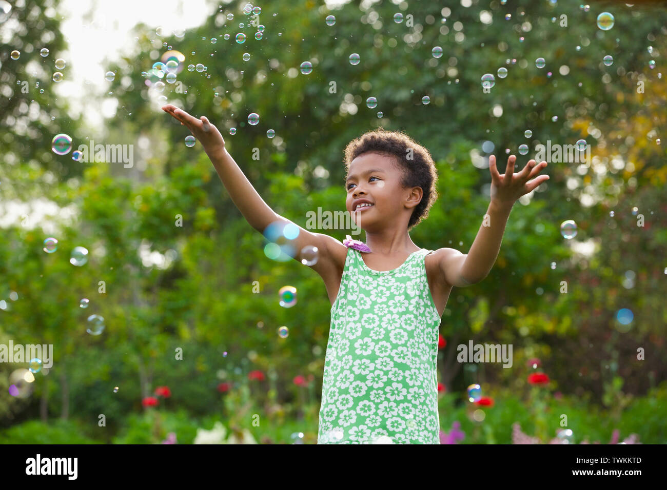 Girl trying to hold floating bubbles Stock Photo