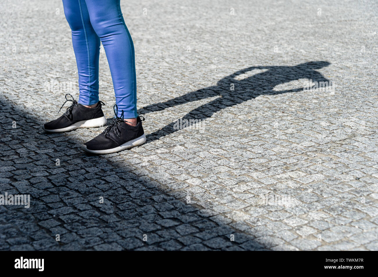 shadow of female runner resting with her hands on hips Stock Photo