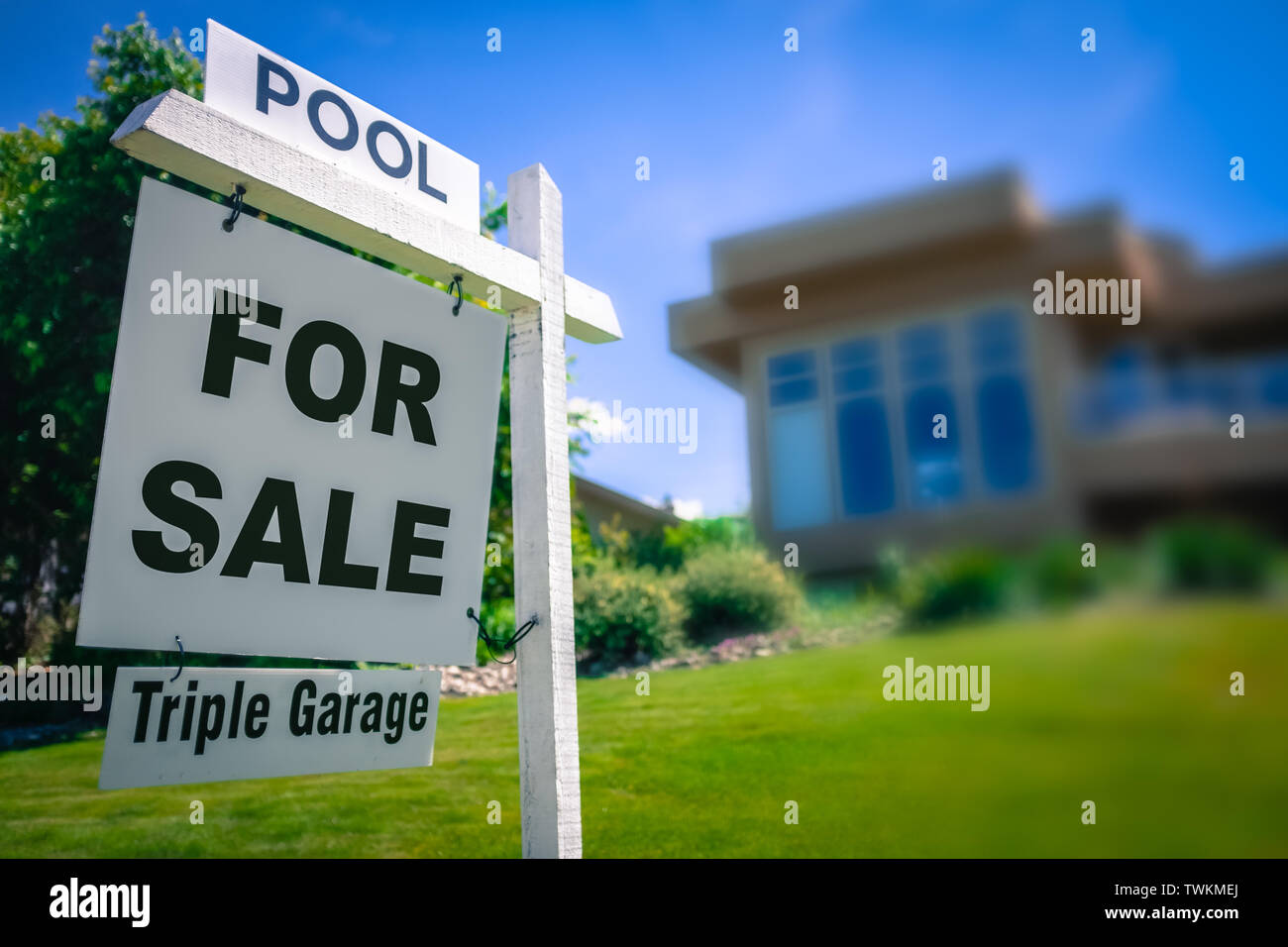 A Sale Sign For A Luxury Home With A Triple Garage And Swimming Pool In The Suburbs Stock Photo