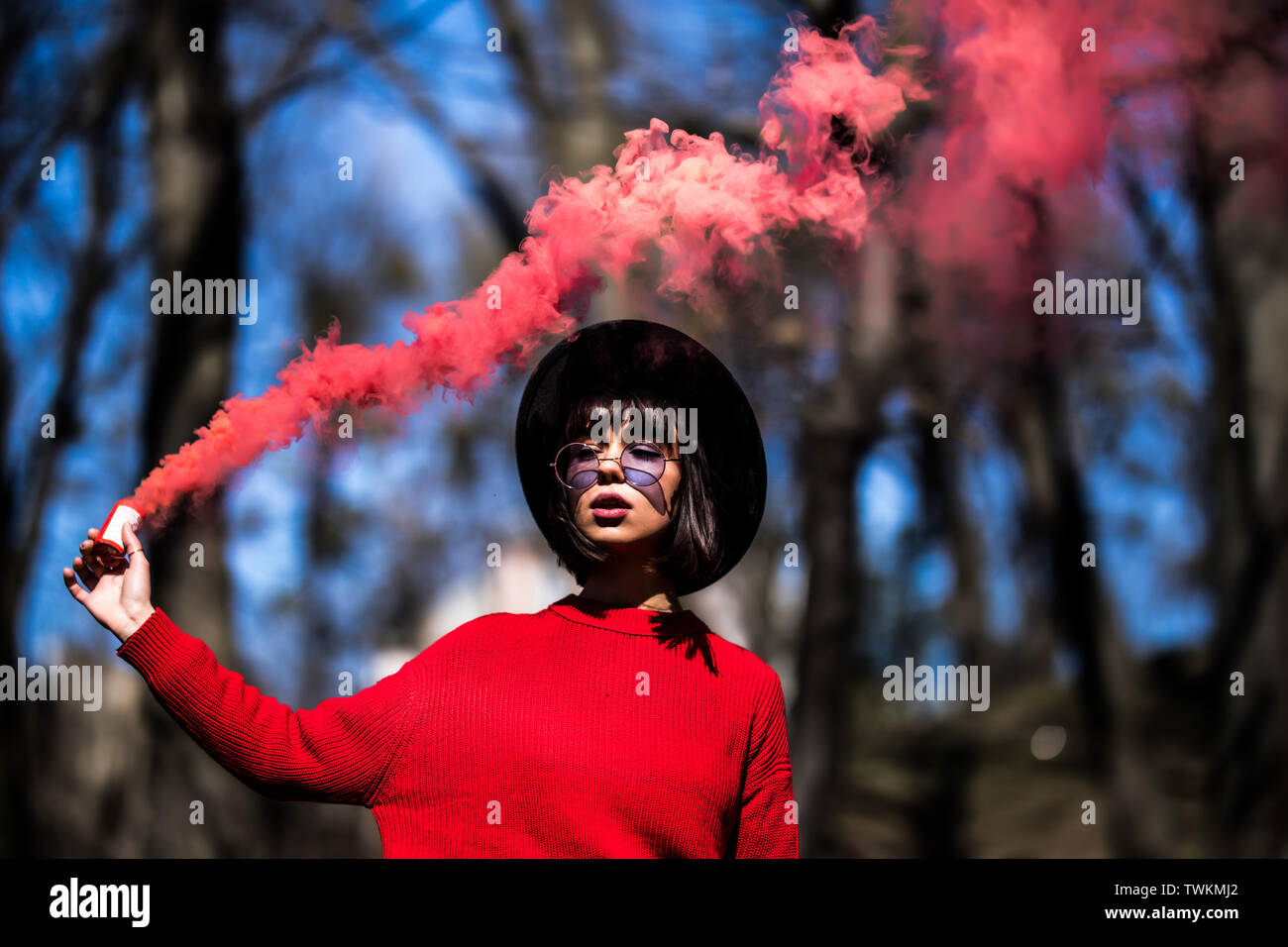 Young woman holding red colorful smoke bomb on the outdoor park.Red smoke  spreading in the cerebration festival Stock Photo - Alamy