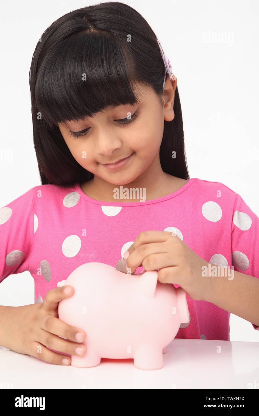 Girl putting a coin into a piggy bank Stock Photo - Alamy