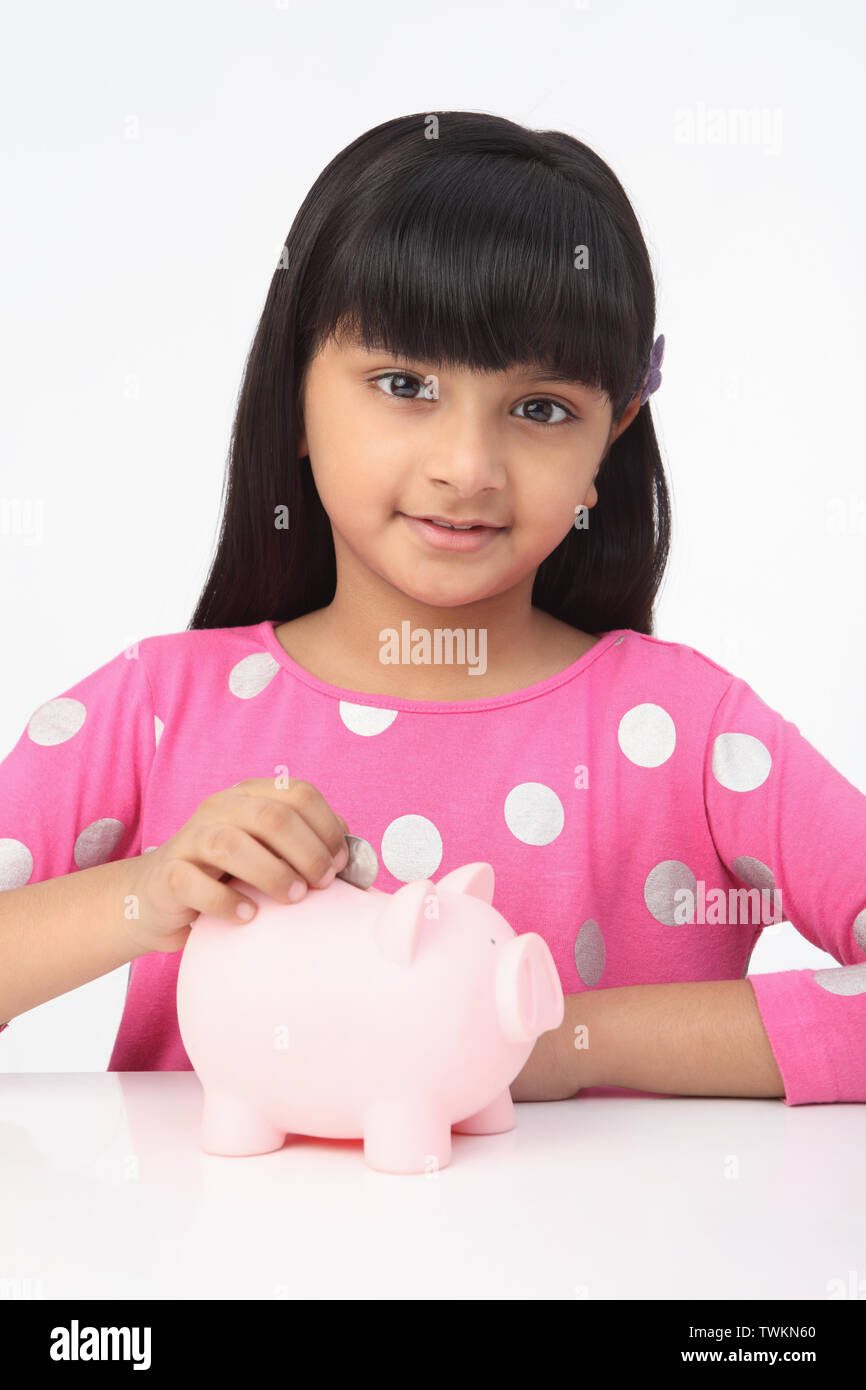 Girl putting a coin into a piggy bank Stock Photo - Alamy