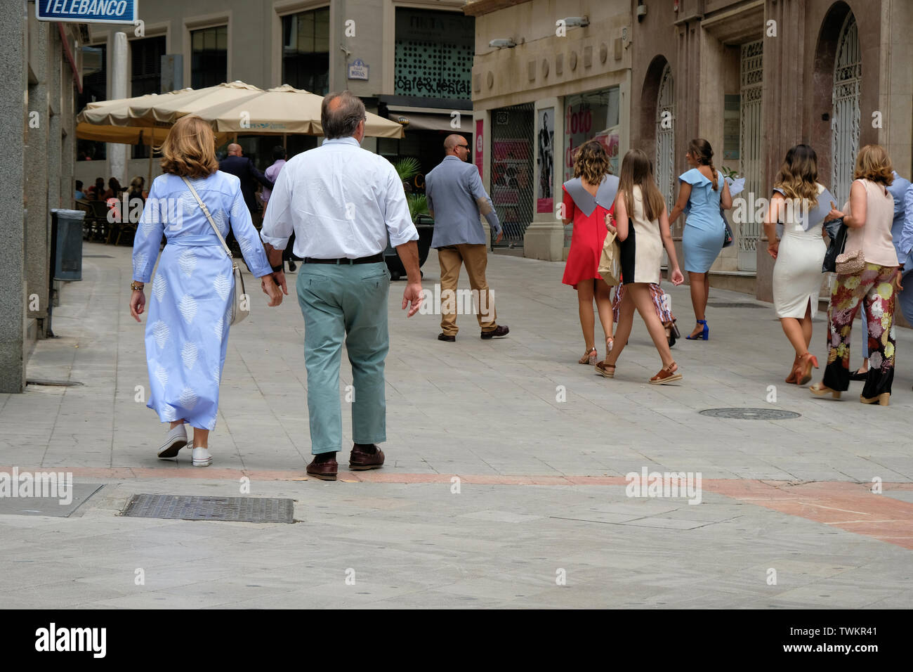 Middle aged couple holding hands while walking down a busy pedestrian walkway in Granada, Spain. Stock Photo