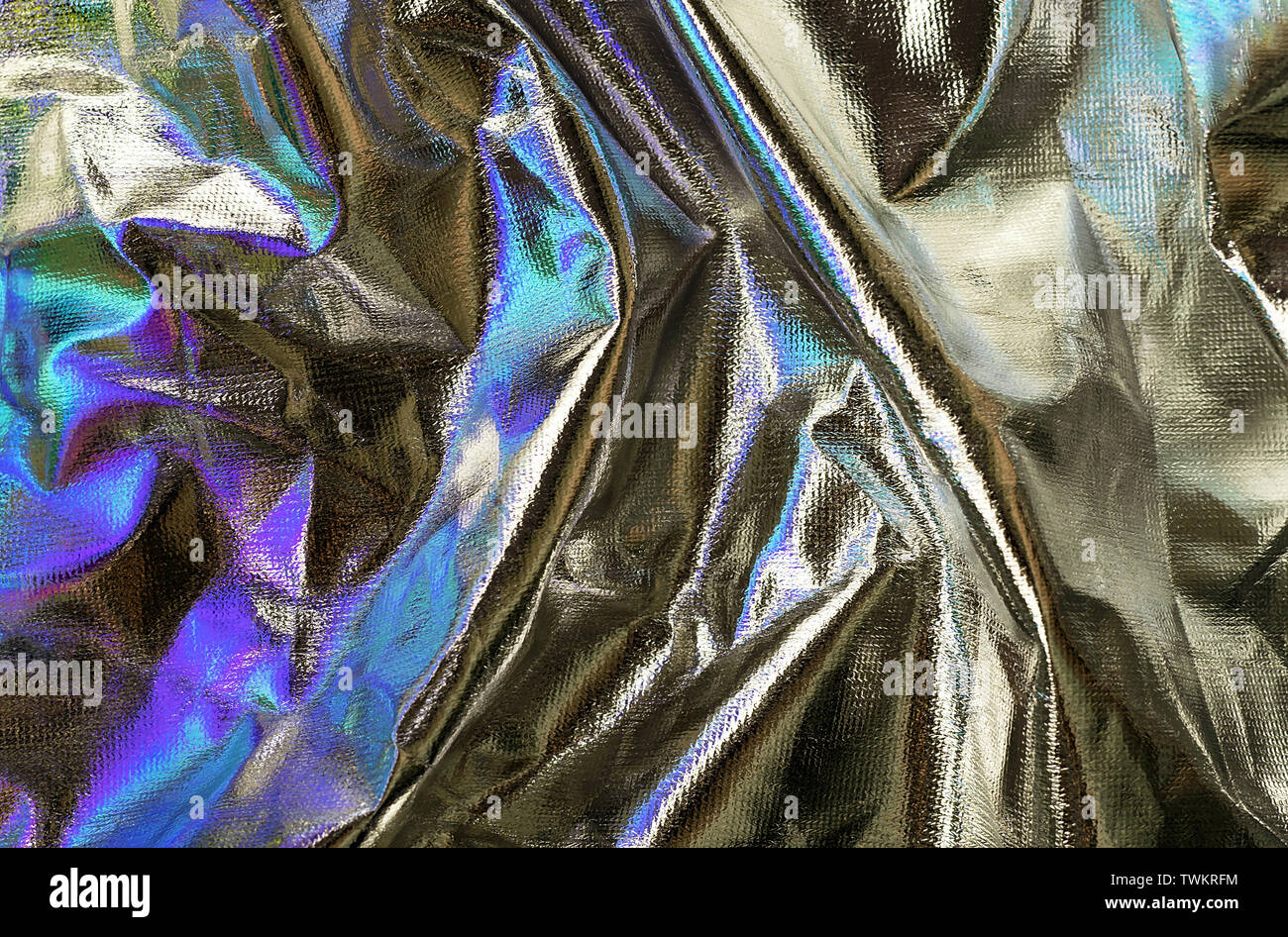 Textured silver foil background with shiny crumpled surface and turquoise and violet reflects. Stock Photo