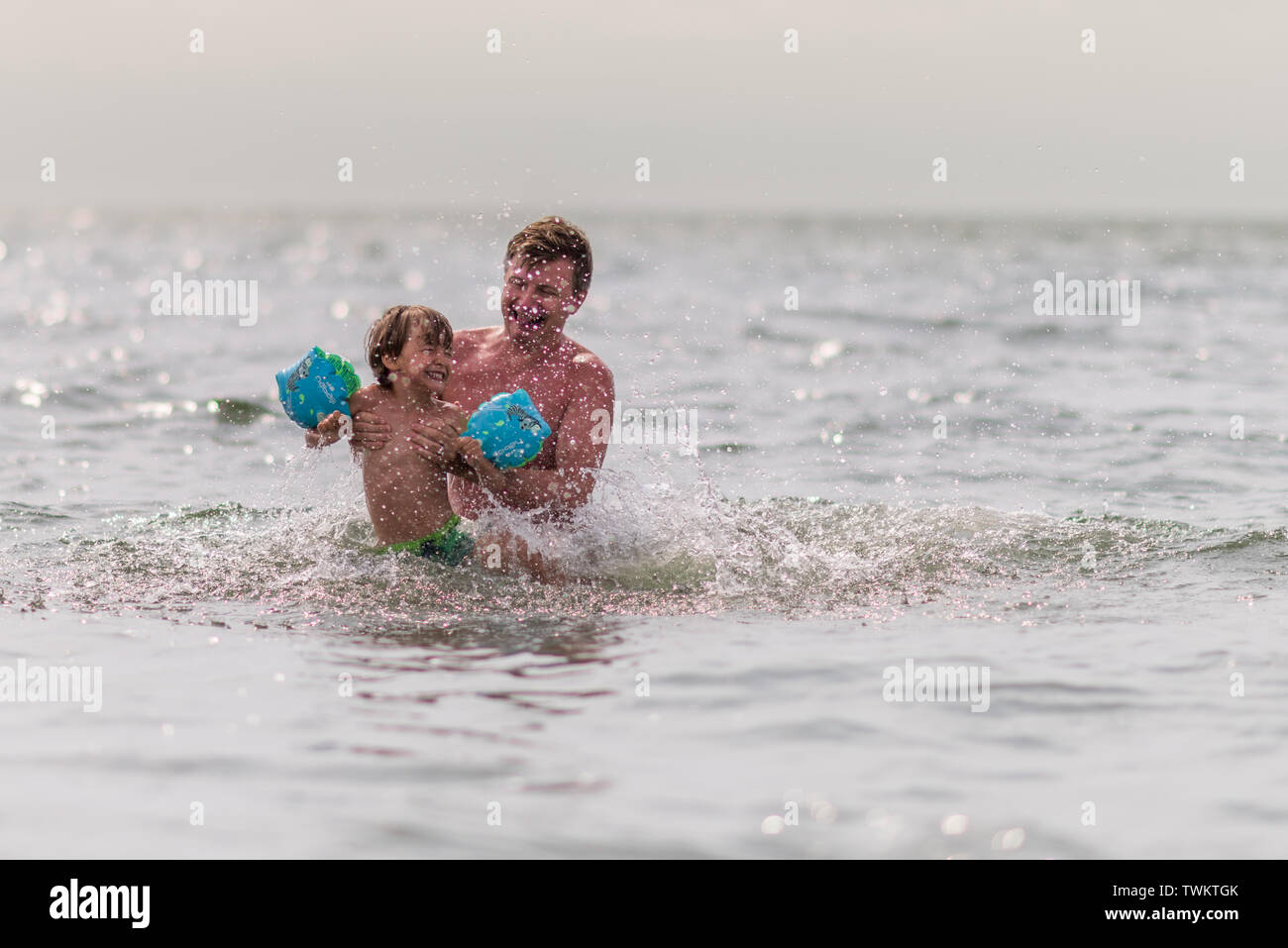 Among the water droplets, in the sea, in the sun, happy with all that life offers to them, spending quality time together, the two men in the photo ar Stock Photo