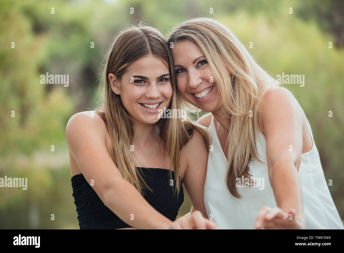A beautiful mother and her daughter and standing side by side outdoors, laughing together and looking carefree. Stock Photo