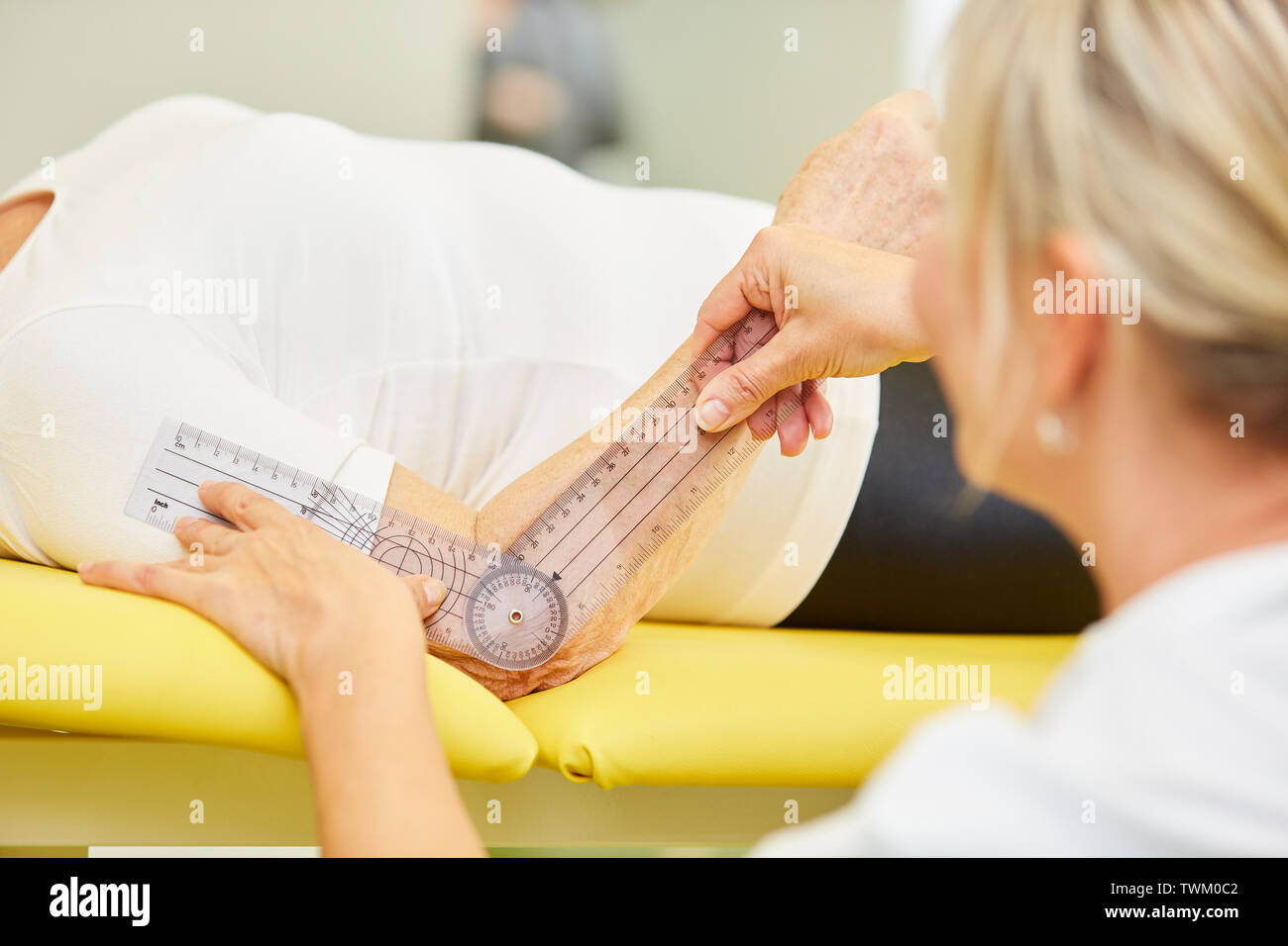 Physiotherapist using a goniometer to measure elbow joint mobility Stock Photo
