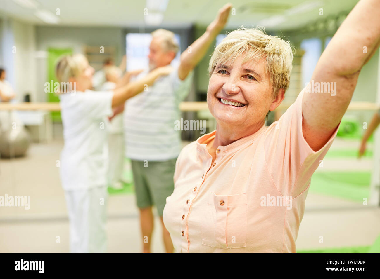 Happy senior woman is doing a back exercise in fitness class in gym ...