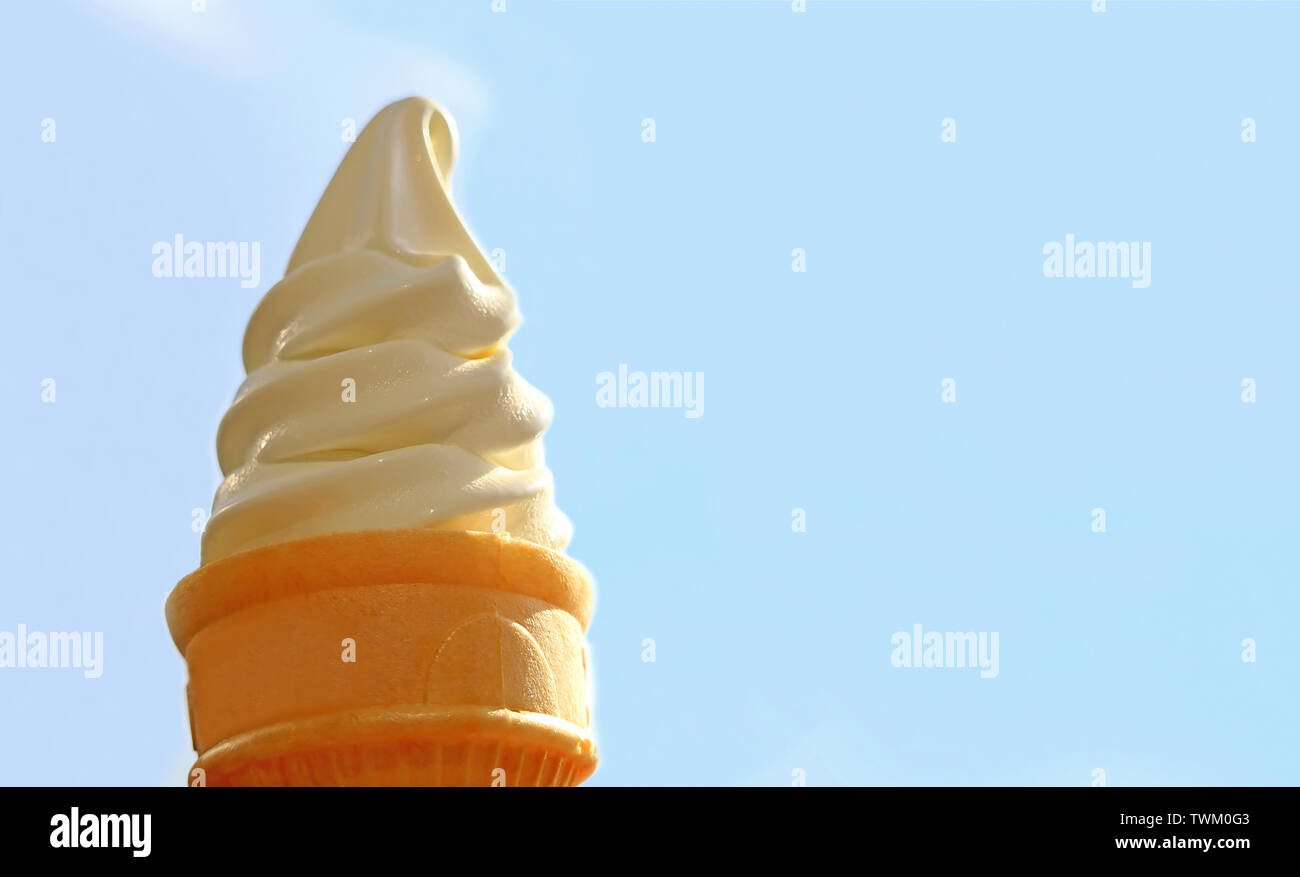 Vanilla Soft Serve Ice Cream Cone Against Sunny Blue Sky with Copy Space Stock Photo