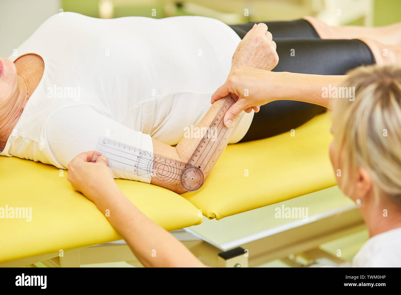 Female doctor measuring elbow mobility with the goniometer in physiotherapy Stock Photo