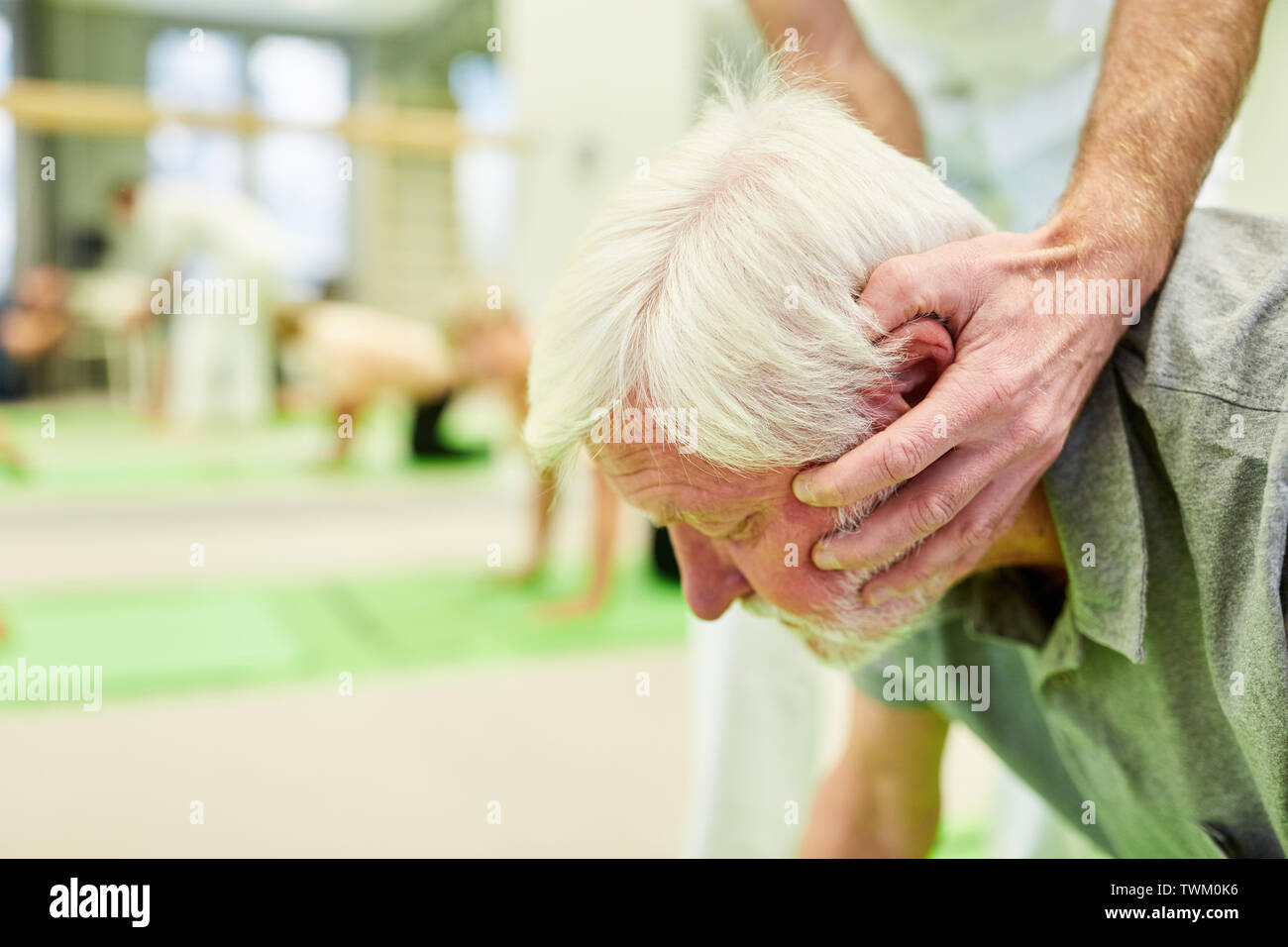 Chiropractor or physiotherapist helps senior patient with a rehab exercise for the neck Stock Photo