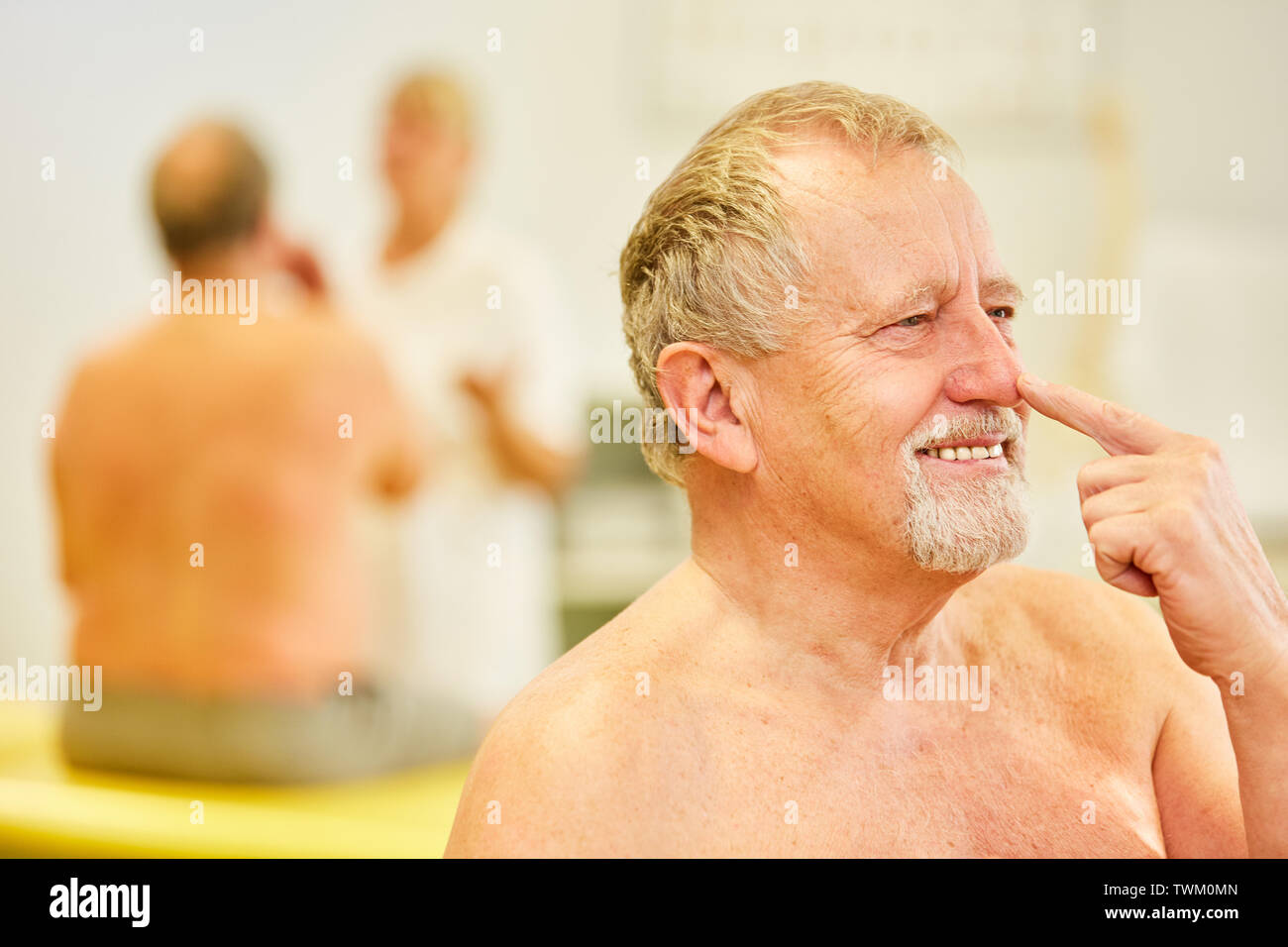 Senior man with forefinger on nose at finger-nose-try at the family doctor Stock Photo