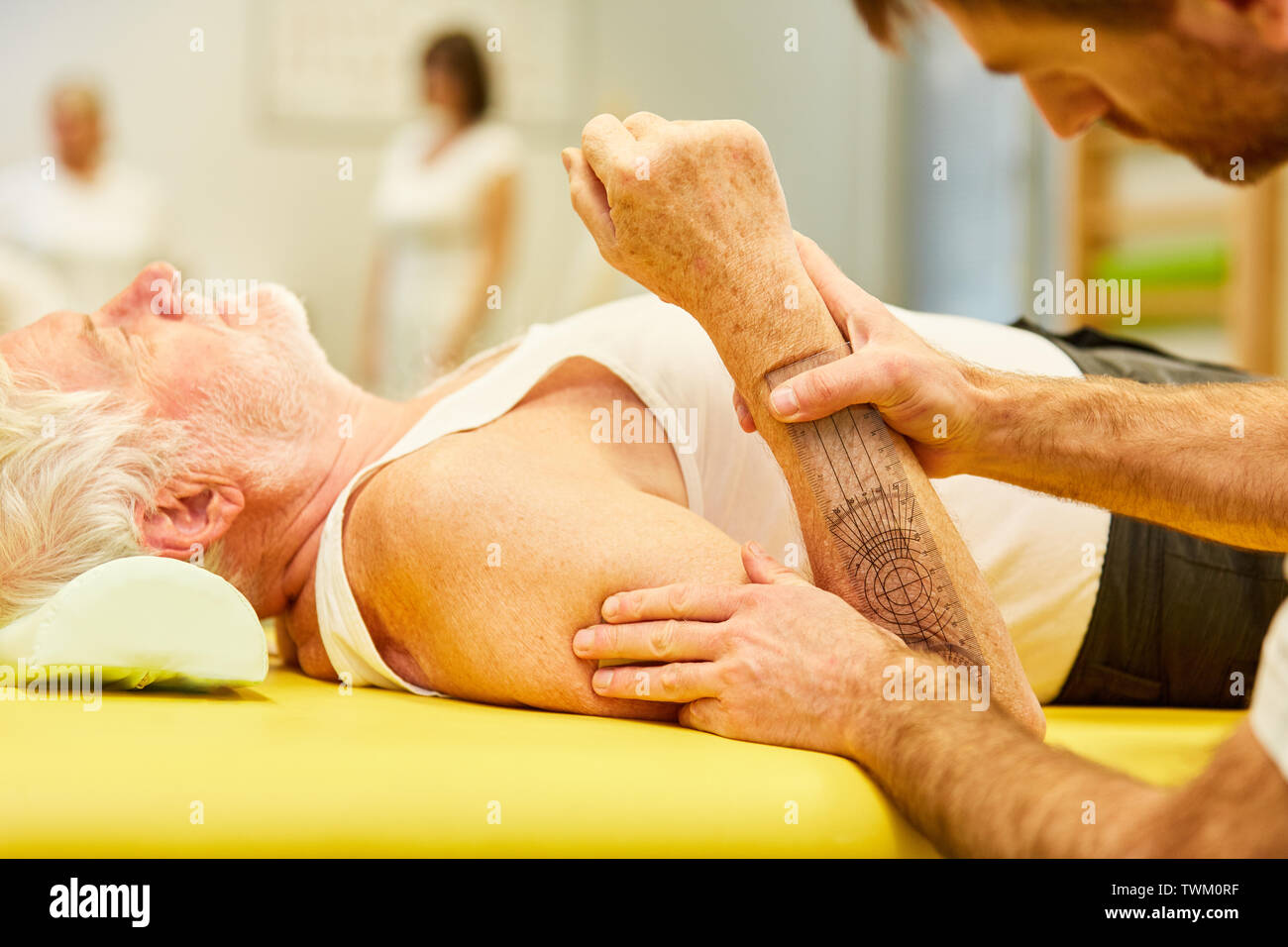 Physiotherapist measuring elbow mobility of patient with goniometer Stock Photo