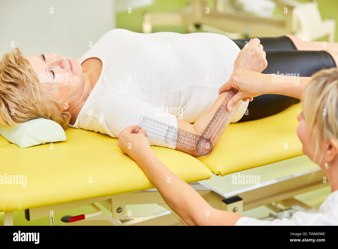 Non-medical practitioner measuring the mobility of the elbow of the patient with the goniometer Stock Photo