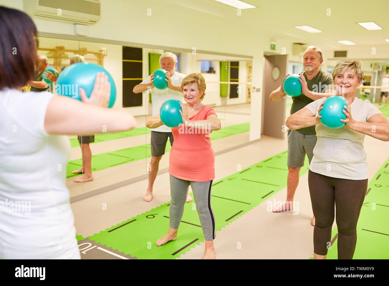 Group of seniors exercises with the mini gym ball in the back school of